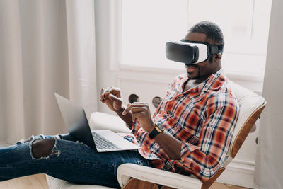 Young woman using mobile phone while sitting on sofa at home