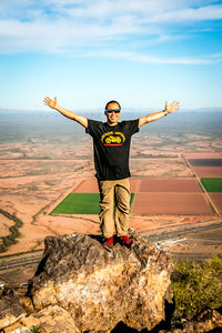 Portrait of man with arms outstretched standing on landscape