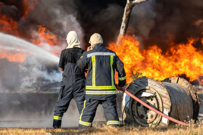 Fireman or firefighter spraying water from big water hose to prevent fire