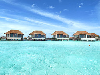 Stilt houses by swimming pool against sky