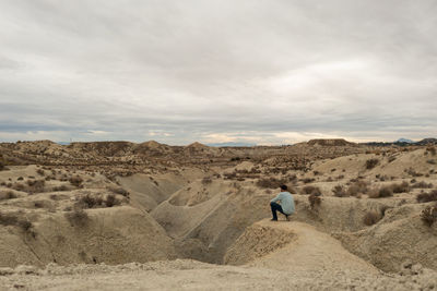 Rear view of man walking on landscape against sky