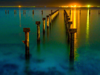 Wooden posts in lake at night