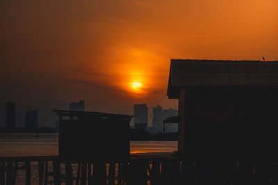 Silhouette buildings against romantic sky at sunset