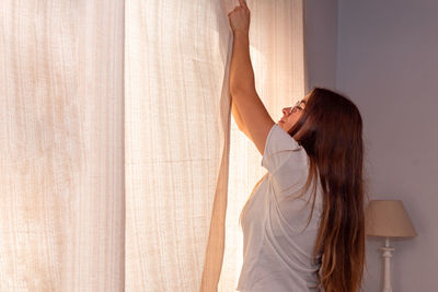 Side view of young woman standing in curtain
