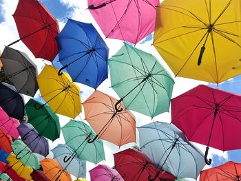 Low angle view of multi colored umbrellas hanging against sky