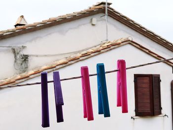 Low angle view of clothesline hanging on building against sky