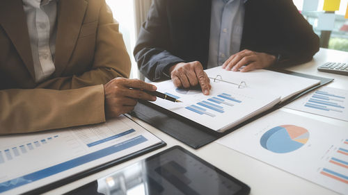 Midsection of business colleagues working at desk in office