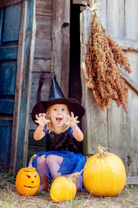 Portrait of smiling young woman sitting by pumpkin