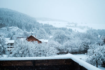 Snow covered houses and trees against sky