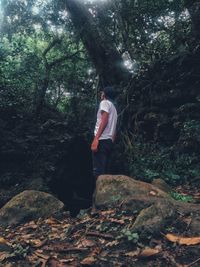 Rear view of man walking on rock in forest