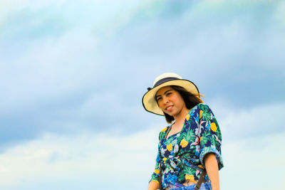 Low angle portrait of woman standing against sky