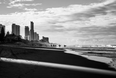 Scenic view of beach by buildings against sky