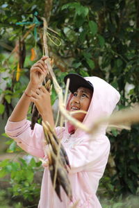 Teenage boy hanging decoration on branch