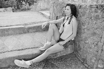 Portrait of young woman sitting on retaining wall