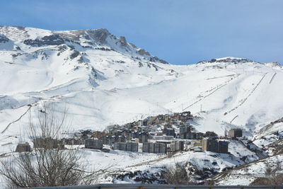 Snow covered houses by buildings against sky