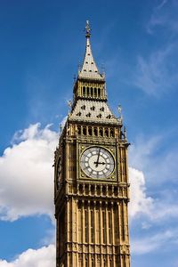 Low angle view of clock tower against cloudy sky