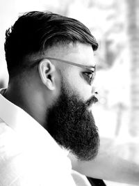 Side view of young man wearing sunglasses looking away while sitting outdoors