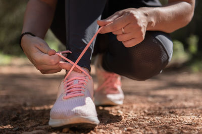 Low section of woman tying shoelace