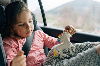 Side view of girl blowing bubbles in car