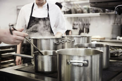 Cropped image of male chef students cooking food in commercial kitchen