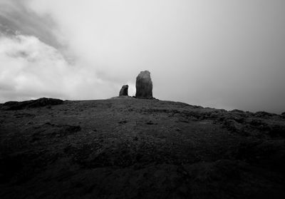 Rear view of man standing on rock against sky