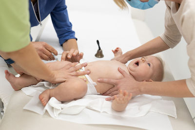 Midsection of doctor examining patient on bed