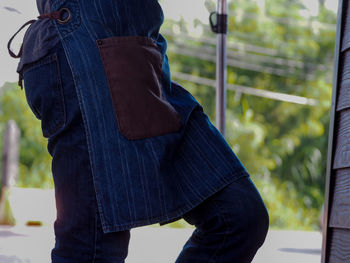 Midsection of woman in apron standing at entrance