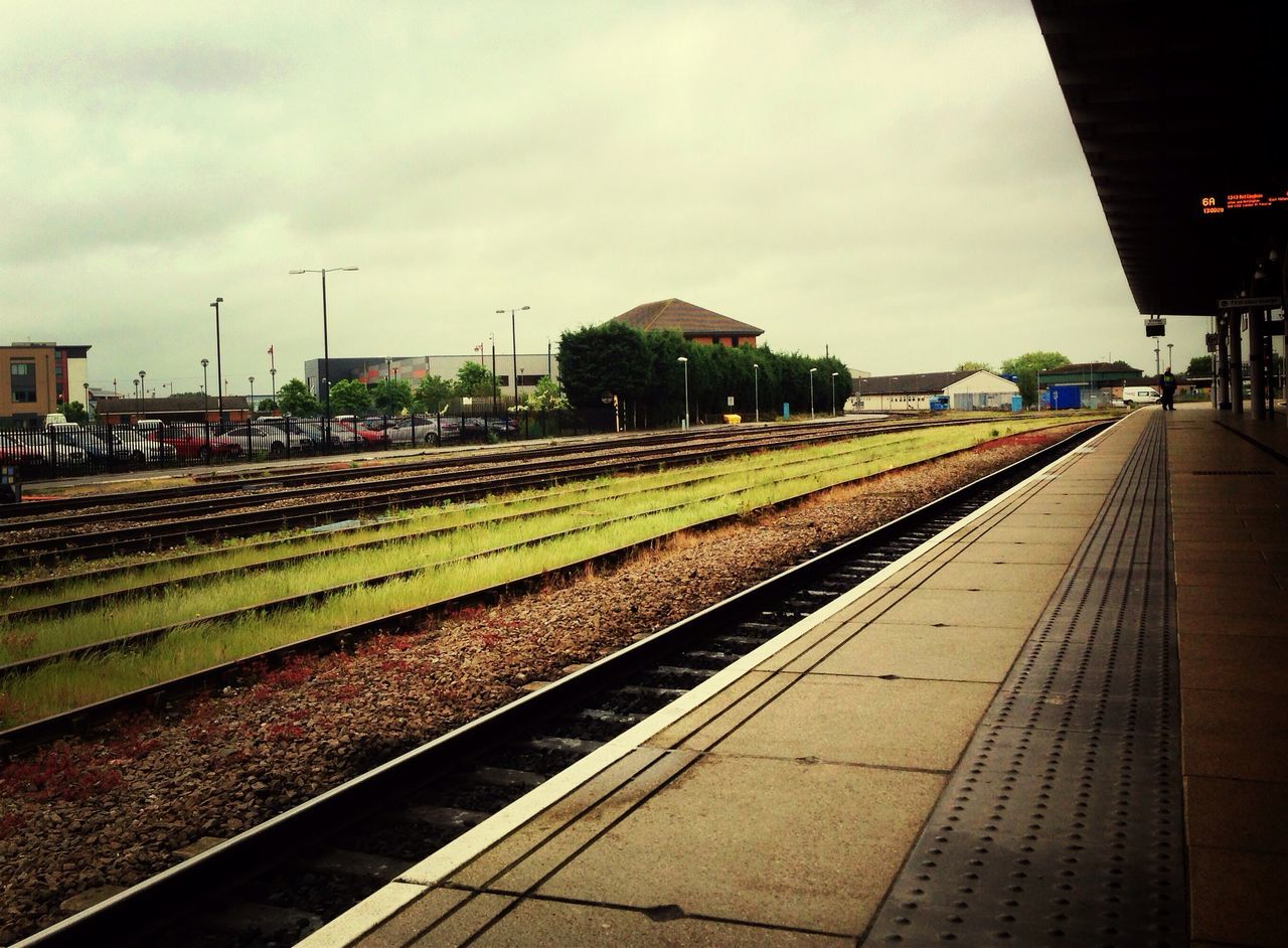 railroad track, rail transportation, transportation, public transportation, railroad station platform, railroad station, sky, building exterior, train - vehicle, built structure, railway track, architecture, the way forward, cloud - sky, vanishing point, diminishing perspective, train, high angle view, travel, city