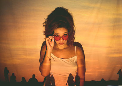 Portrait of woman standing against orange sunset