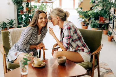 Two women sitting in a tropical restaurant having fun discussing