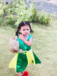 Portrait of cute girl with toy standing on field