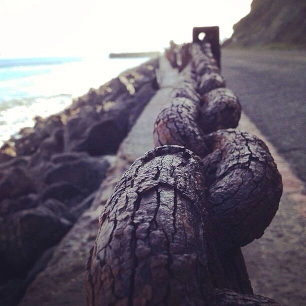 focus on foreground, close-up, textured, wood - material, sea, sky, rock - object, nature, outdoors, day, rough, beach, selective focus, balance, no people, sculpture, sunlight, art and craft, art, tranquility