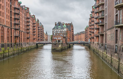 Canal amidst buildings in city against sky