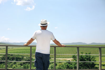 Rear view of man standing on field against clear sky