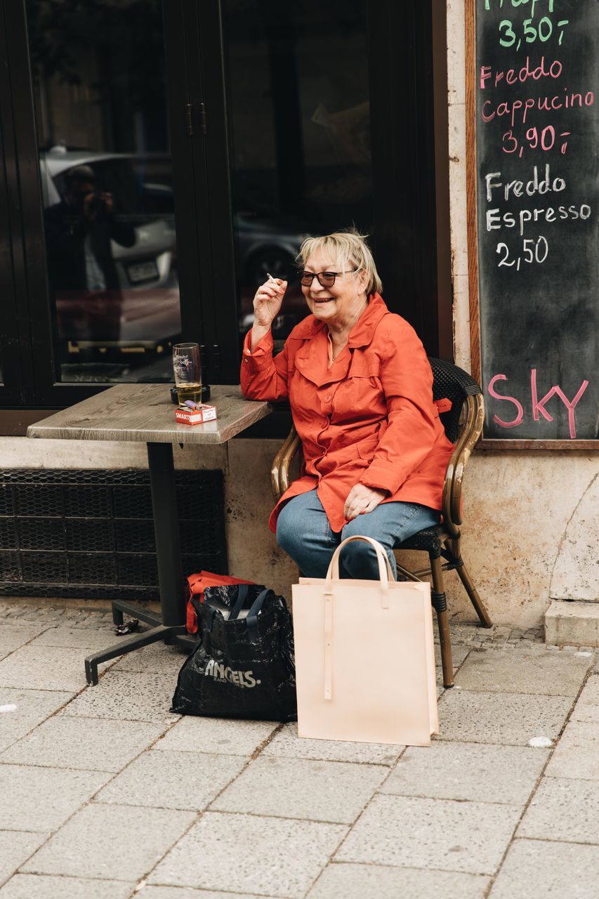 MIDSECTION OF WOMAN SITTING ON FOOTPATH AT SIDEWALK