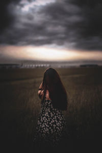 Woman standing on land against sky during sunset