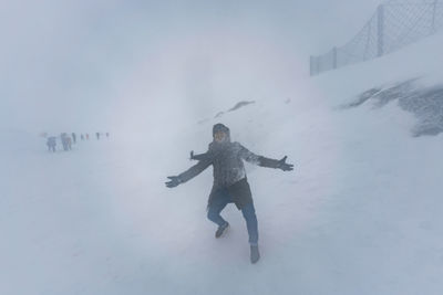 Full length of man standing on snow during blizzard