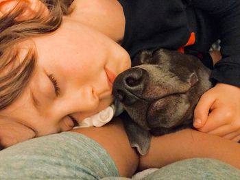 Close-up of boy sleeping with dog on bed at home