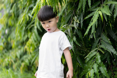 Cute boy standing against plants