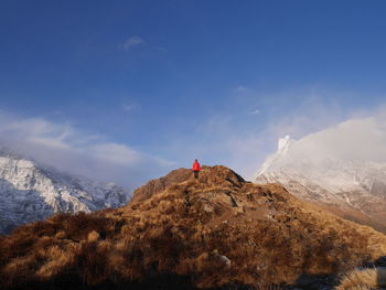 Low angle view of female hiker standing on mountain against blue sky