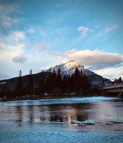 Scenic view of lake by snowcapped mountains against sky