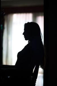 The silhouette of a woman sitting on a chair