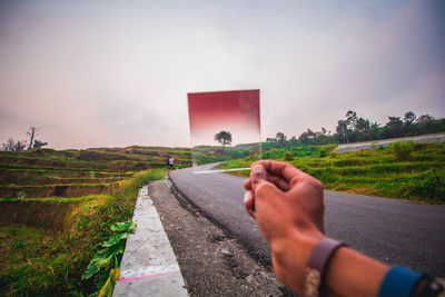 Man skateboarding on road against sky