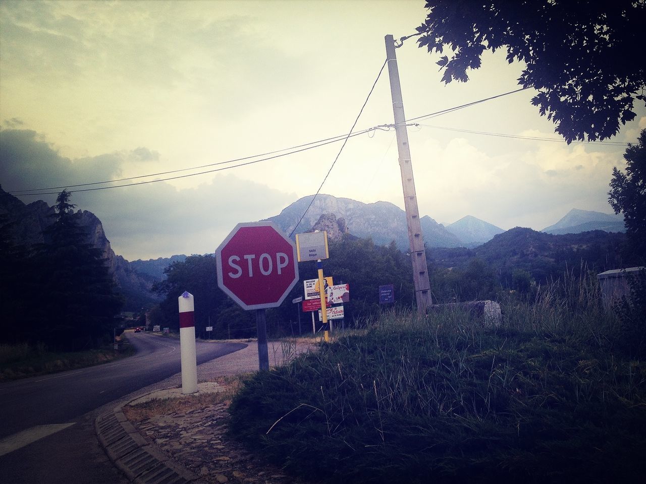 sky, mountain, text, communication, road, transportation, road sign, western script, cloud - sky, tree, sign, guidance, plant, information sign, the way forward, landscape, nature, red, day, tranquility