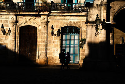 Silhouette woman walking by building in city