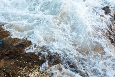 High angle view of waves breaking on rocks