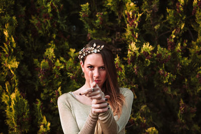 Portrait of young woman standing against trees