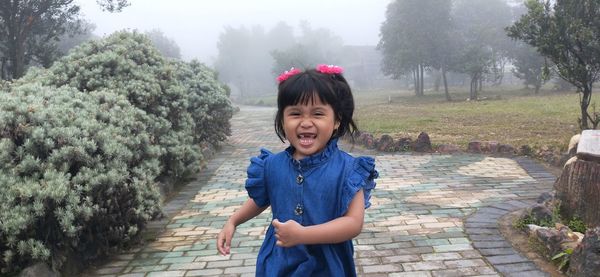 Portrait of smiling girl standing against plants