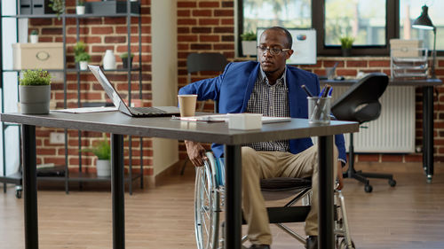 Businessman sitting on wheelchair in office