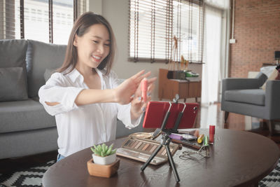 Young woman using mobile phone while sitting on sofa at home